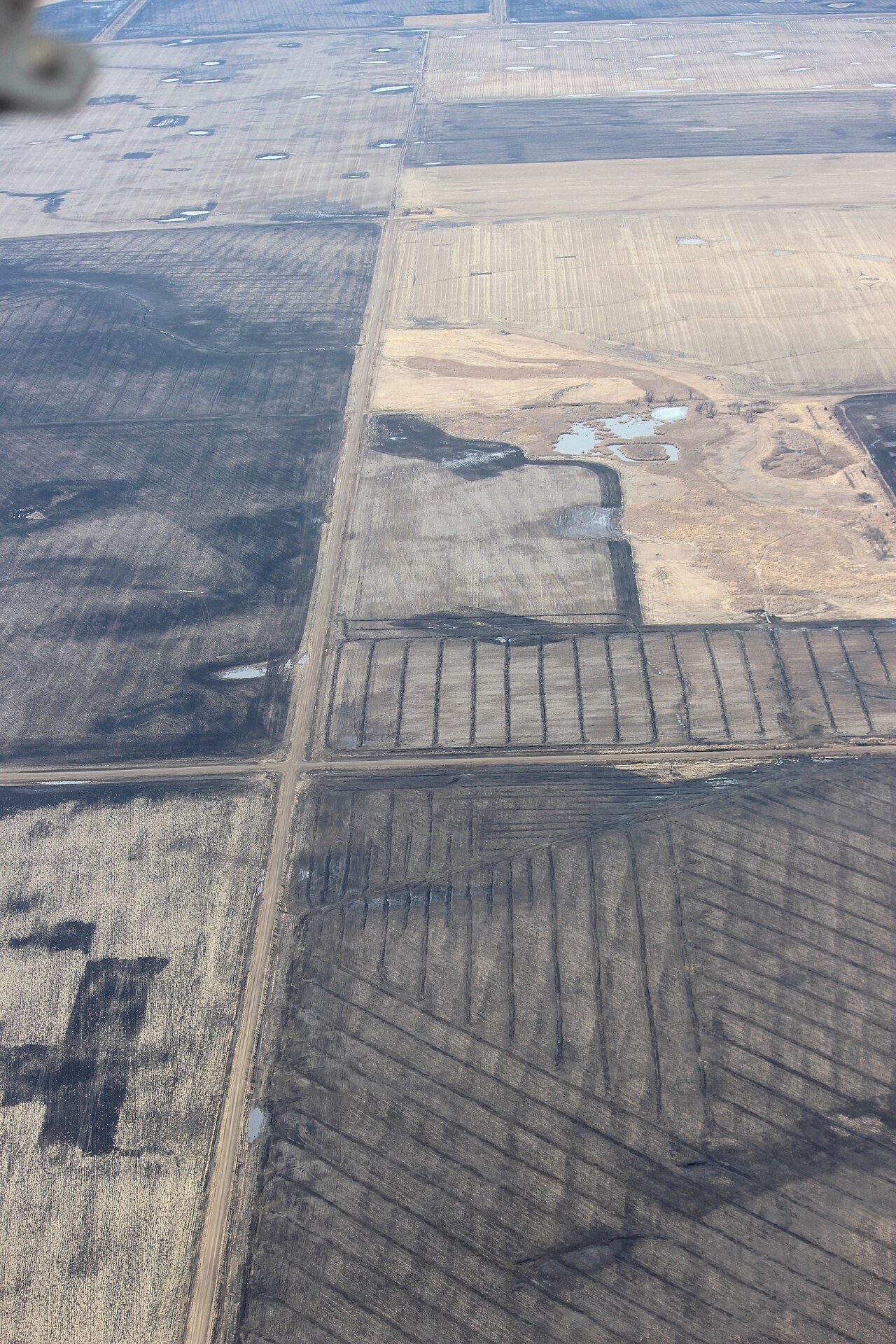 Aerial view of a field showing a regular pattern of laid subsurface (pipe) drainage