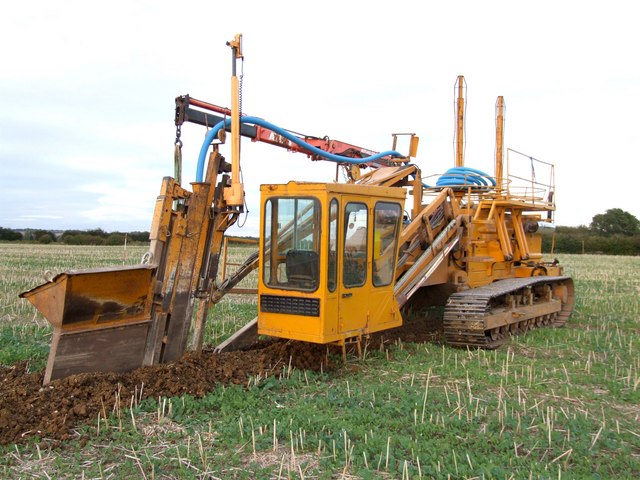 Laying pipe drainage in an excavated trench on agricultural land