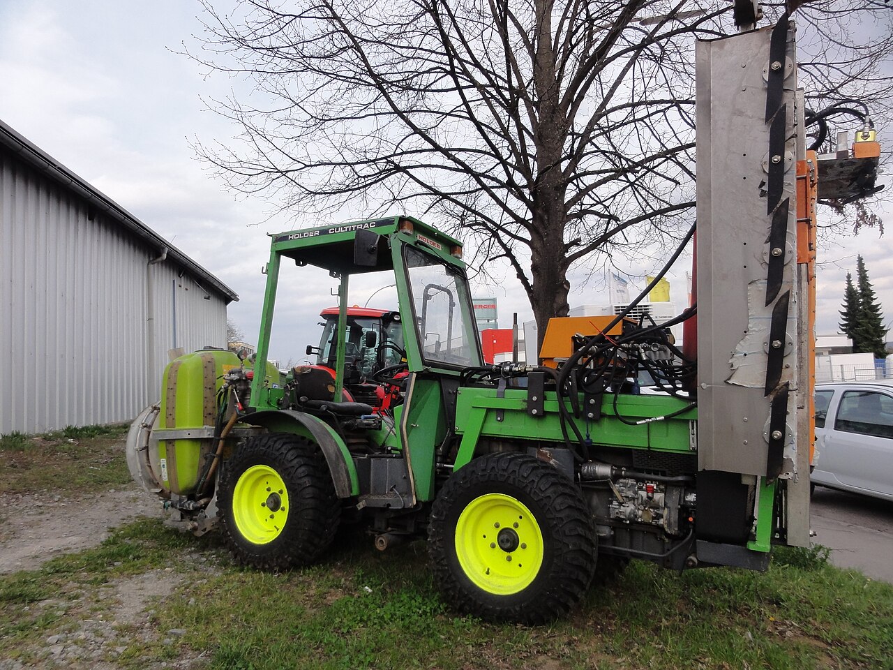 Orchard tractor equipped with a spray tank and row processing attachment